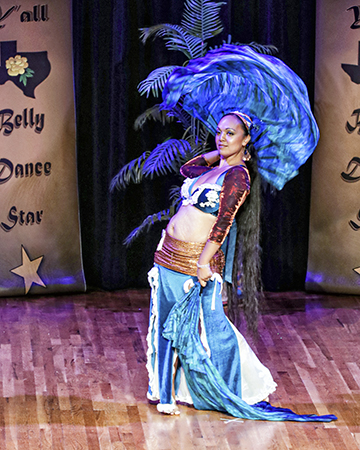 dancer in blue slightly leans backward while moving a silk fan veil behind her head