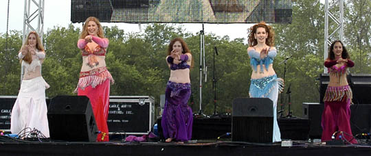 5 members of the Wings of Isis performing on stage, wearing white, pink, purple, pale blue, and dark pink