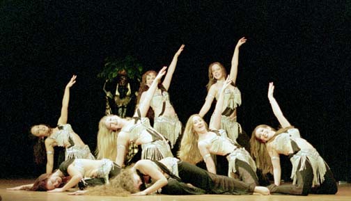 8 dancers in silver bedlah and black pants in ending pose of performance