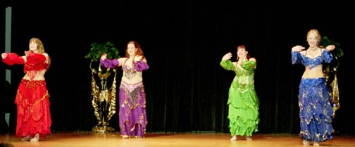 4 dancers perform wearing red, purple, lime green, and blue costumes