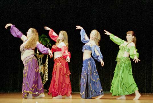 4 dancers perform wearing red, purple, lime green, and blue costumes