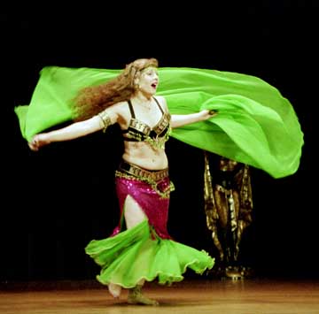 dancer Rachael spins on stage wearing pink and green costume with green veil