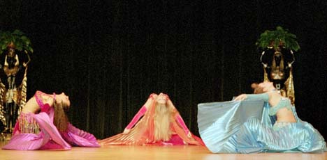 3 dancers perform backbends toward center stage during performance