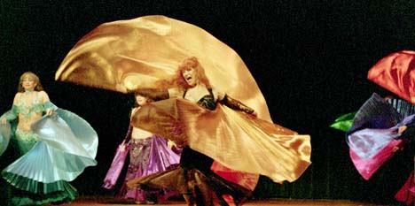 Isis spins with copper veil with Wings of Isis behind her on stage