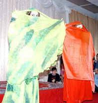 duet of dancers peek out of veils that are green and orange