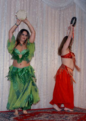dancers wearing green and orange perform with tambourines