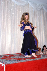 dancer in purple costume with headback performs on stage
