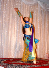 dancer wearing blue and gold costume performs with a purple, blue, and yellow silk veil