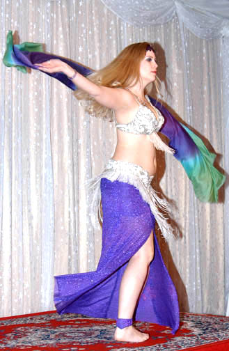 blonde dancer wearing purple and silver spins with a silk veil