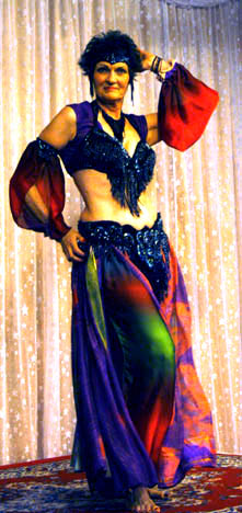 dancer wearing purple, orange, and green poses on stage