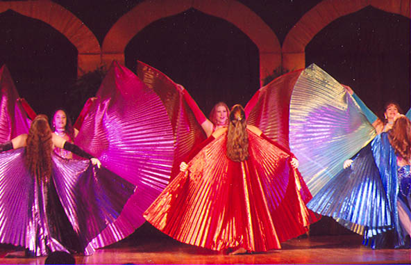 6 dancers performing on stage with metallic wings