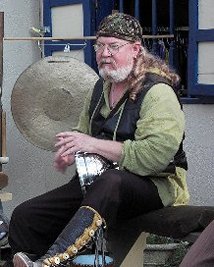 drummer playing silver drum on stage wearing glasses and a head wrap