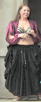 dancer wearing a pink top and full black skirt stands on stage