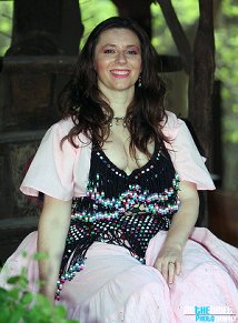 Dancer wearing a black bedlah and pink costume sits and poses for a photo