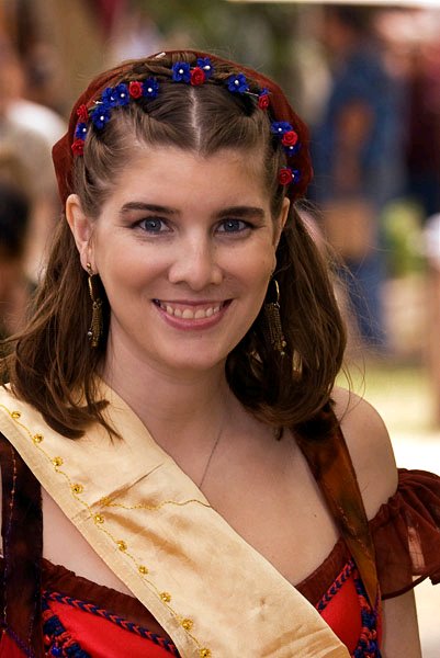 portrait of a dancer with a headband of small red and blue flowers, smiling for the camera