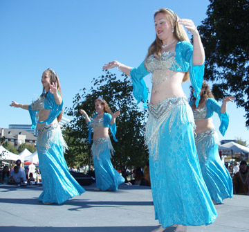 4 dancers in matching turquoise and silver costumes perform together on stage