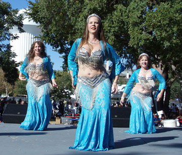 3 dancers in matching turquoise and silver costumes perform together on stage