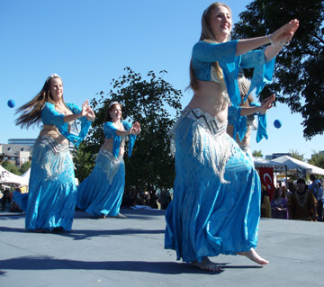 4 dancers in matching turquoise and silver costumes perform together on stage