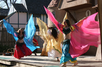 trio of dancers in red, turquoise, yellow, and pink perform with veils outstretched