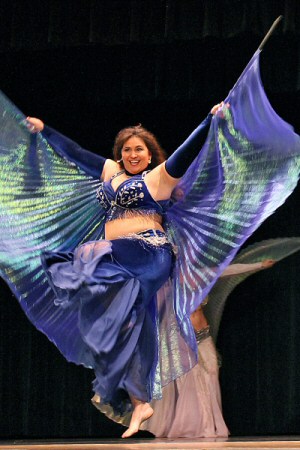 dancer wearing all blue smiles white performing energetically using blue wings