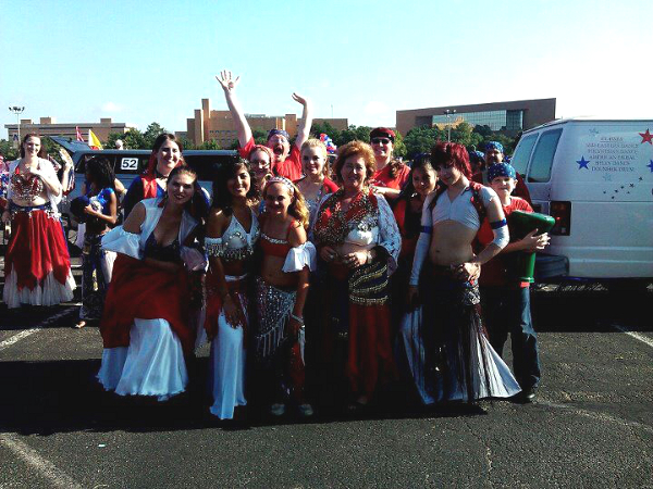 a group of dancers wearing red, white, and blue poses for a photo while waiting for the parade to begin