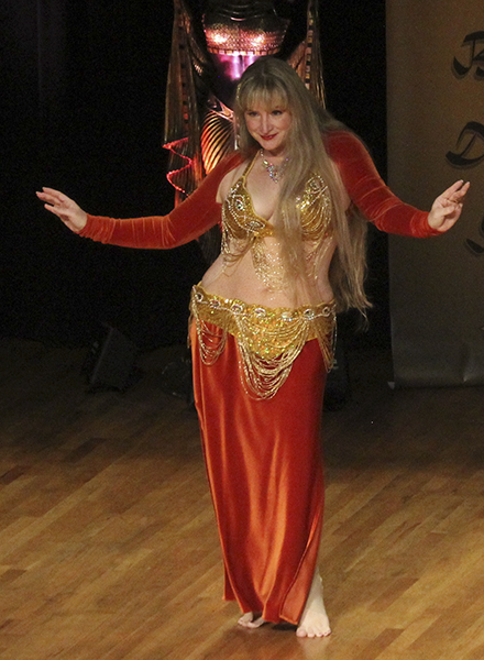 Helena in deep orange performing on stage