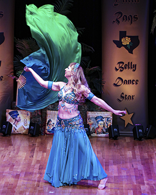dancer wearing blue costume dances with a blue and green fan veil on stage
